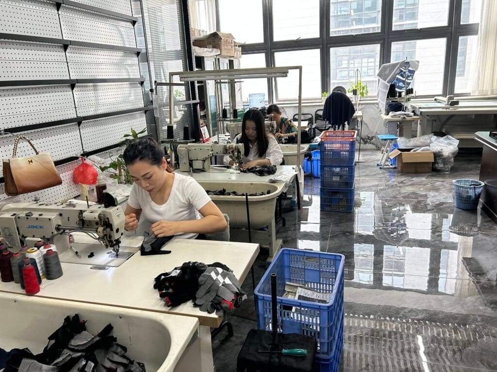 View of a modern heated clothing factory assembly line in Dongguan, China, with workers conducting quality control checks on garments.