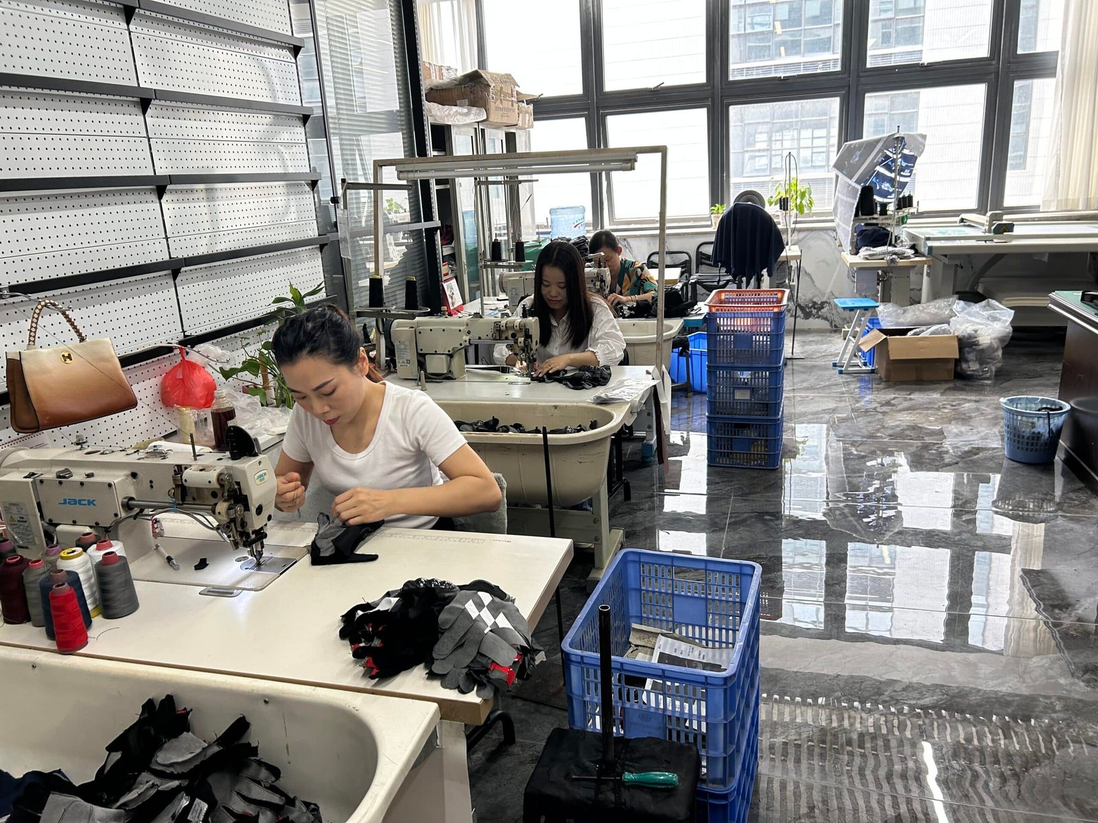 View of a modern heated clothing factory assembly line in Dongguan, China, with workers conducting quality control checks on garments.
