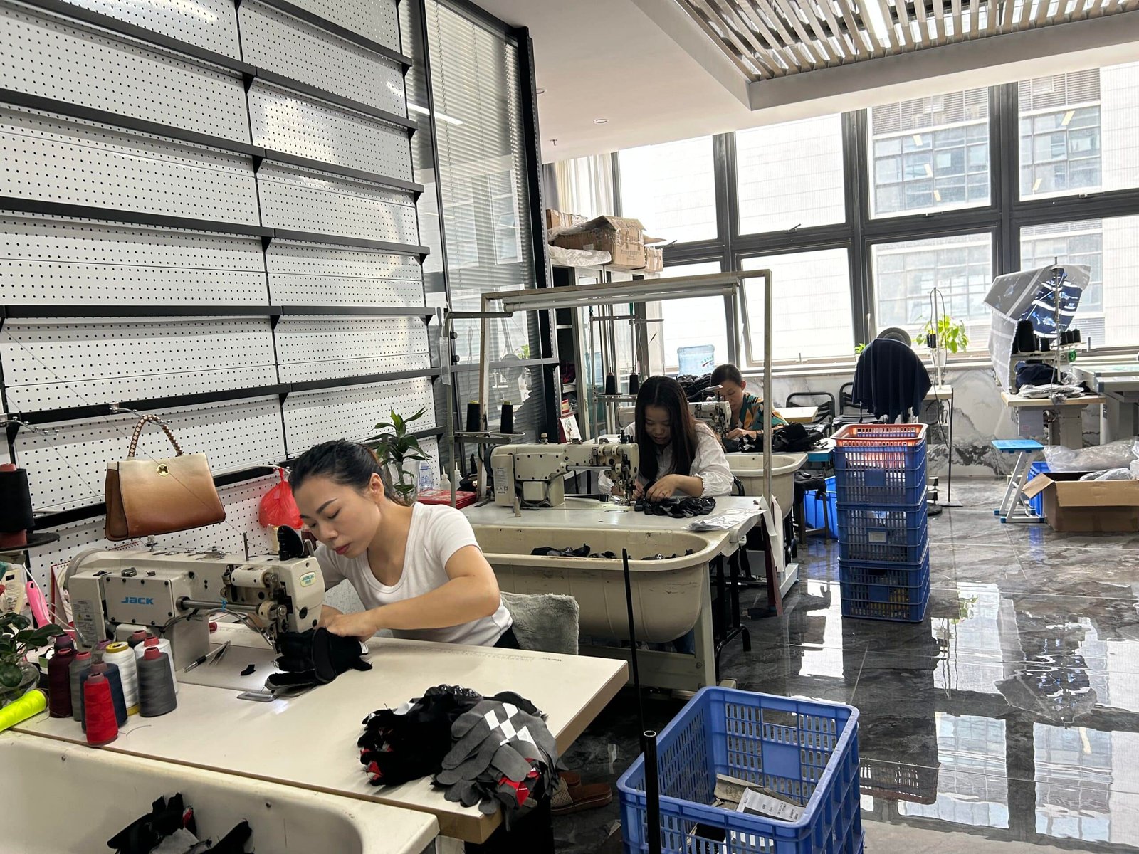 A skilled factory worker in a quality control setting carefully sewing a heated jacket, showcasing the manufacturing process of Dr. Warm heated apparel with attention to detail and safety standards.