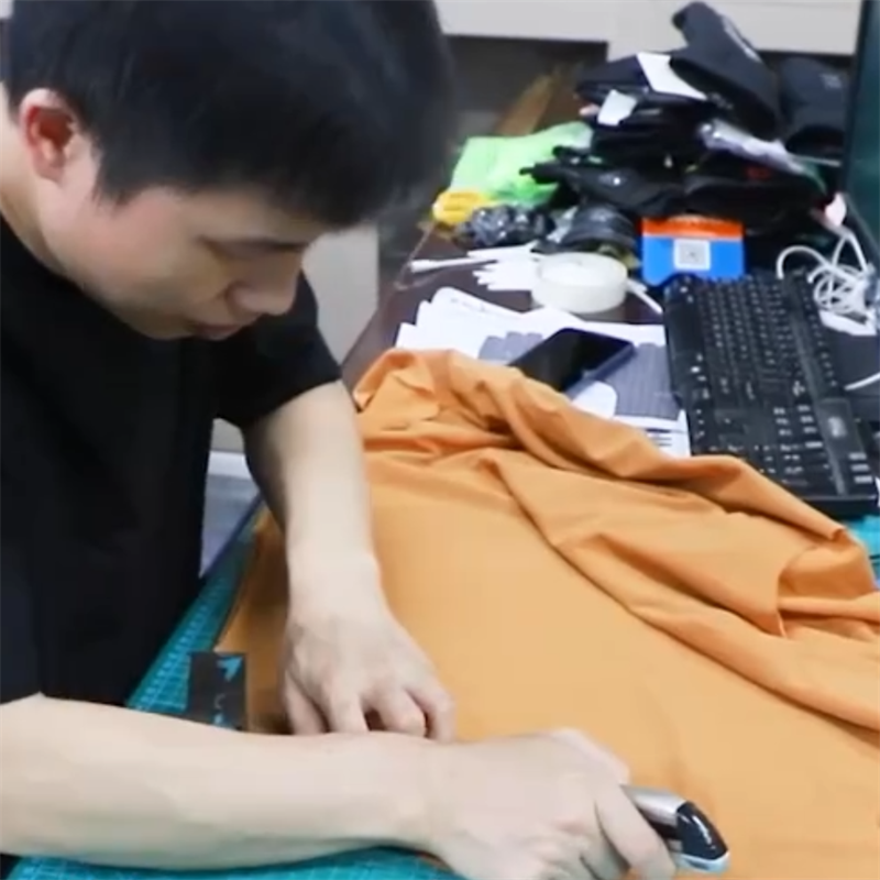 worker cutting fabric for heated clothing production preparing materials for electric heated apparel manufacturing