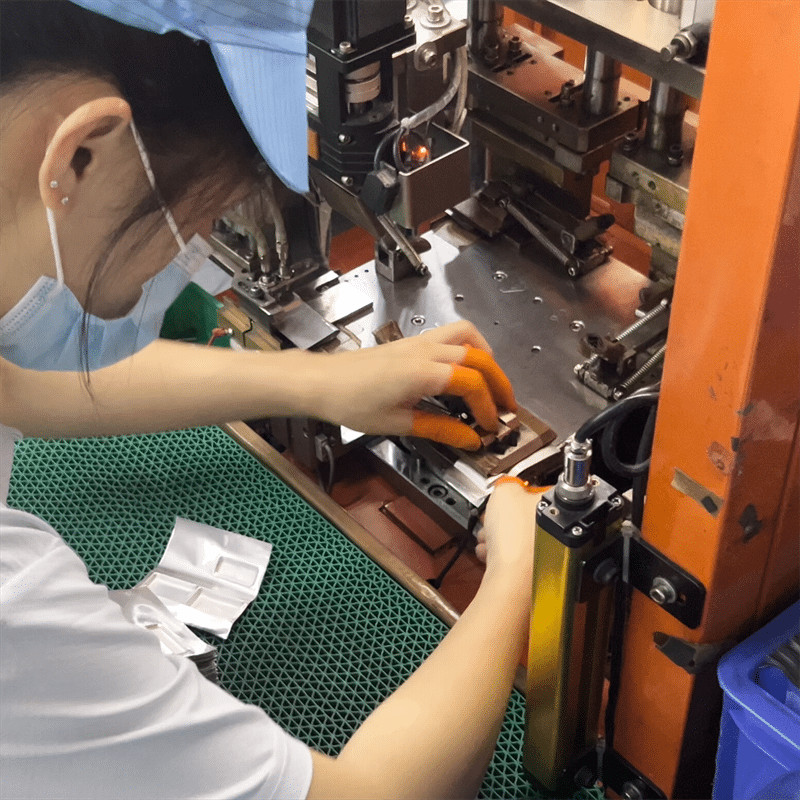 worker operating heat press machine forming heating elements structure for heated clothing production
