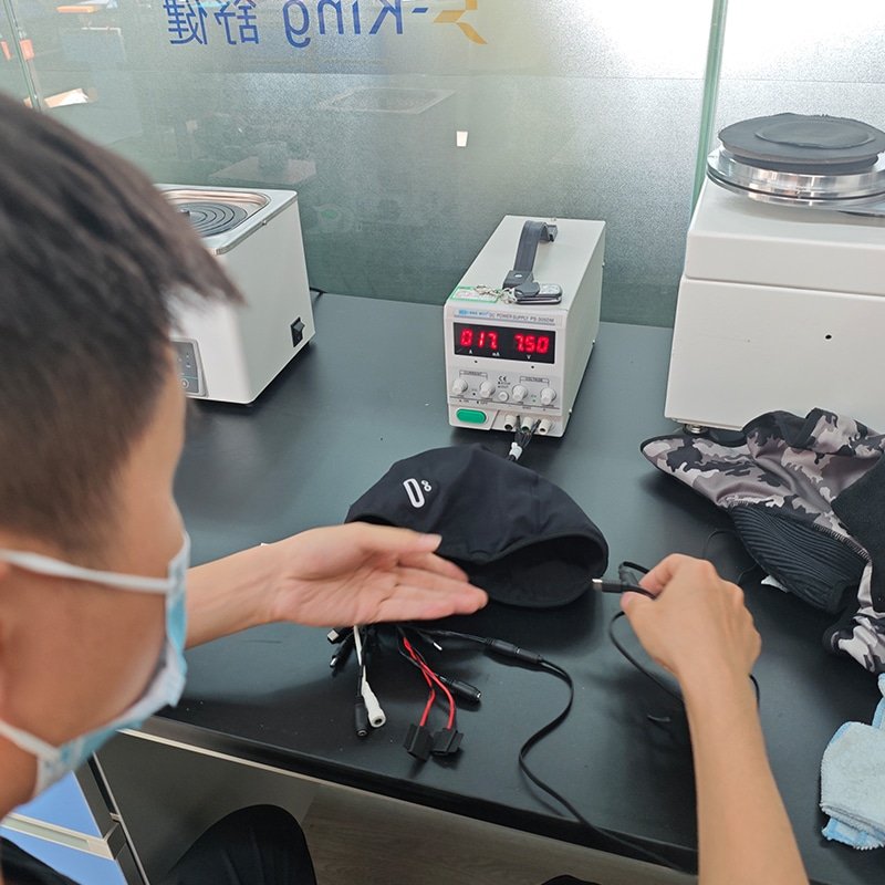 technician testing heated clothing electrical system and heating elements performance in quality control laboratory