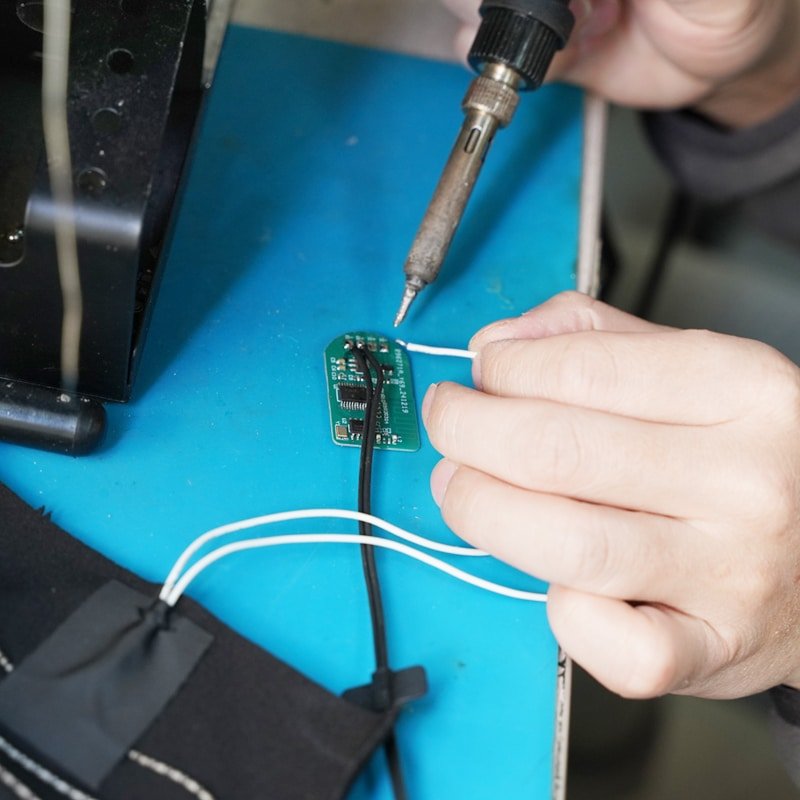 worker soldering PCBA circuit board for heated gloves smart heating system OEM battery control board assembly electronic manufacturing process