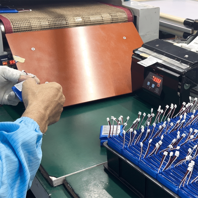 worker assembling and testing rechargeable lithium battery packs with connectors OEM battery production for heated gloves heated apparel quality inspection process