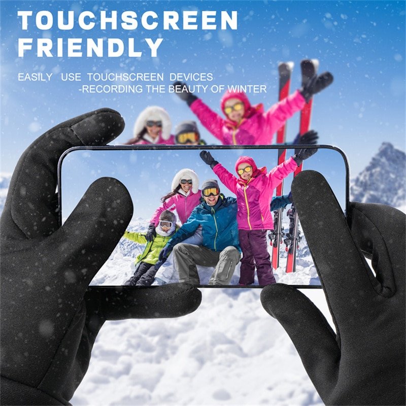 A skier using a smartphone with their fingertip while wearing Dr.Warm G43 touchscreen-compatible heated gloves on a snowy mountain.