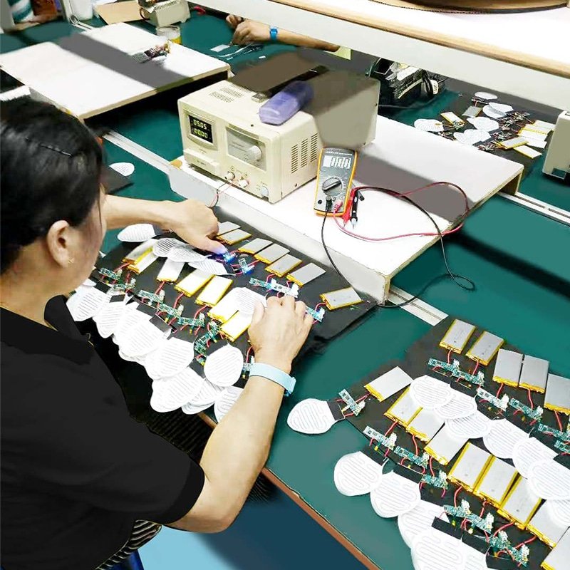 technician assembling battery packs and heating elements for heated apparel electronics systems