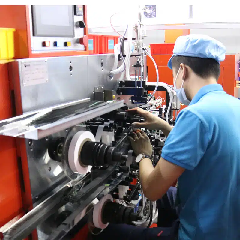 Technician operating automated machine for heated apparel heating element production used in heated clothing systems